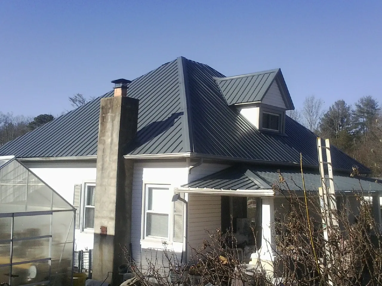 Dark blue standing seam metal roof on a white farmhouse with dormer — Slate & Tile Roof Repair by Roofing Brothers in Onamia