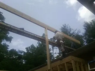 Carpenter setting a ridge beam over a new addition frame — Ice Dam Removal by Roofing Brothers in Onamia