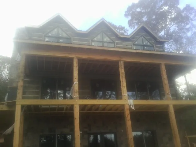 Dormers and porch framing on a large log home under construction — Roof Coating work by our crew in Onamia