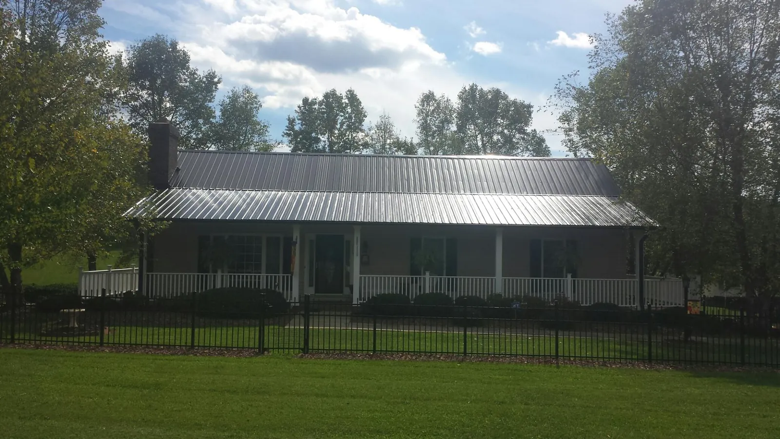 Gray metal roof on a brick ranch with a full width front porch — Gutter Guard Installation work by our crew in Onamia