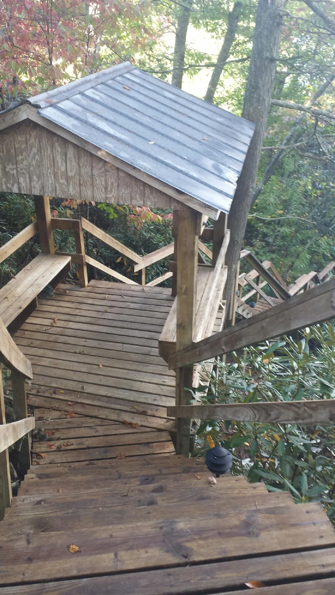 Metal roofed shelter over wooden steps on a wooded walkway — Skylight Repair & Installation work by our crew in Onamia