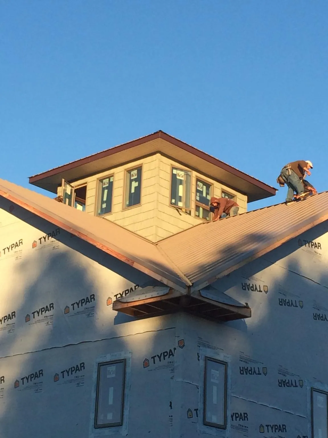 Roofers working around a rooftop cupola on a new metal roof at sunset — Roof Waterproofing in Onamia by Roofing Brothers